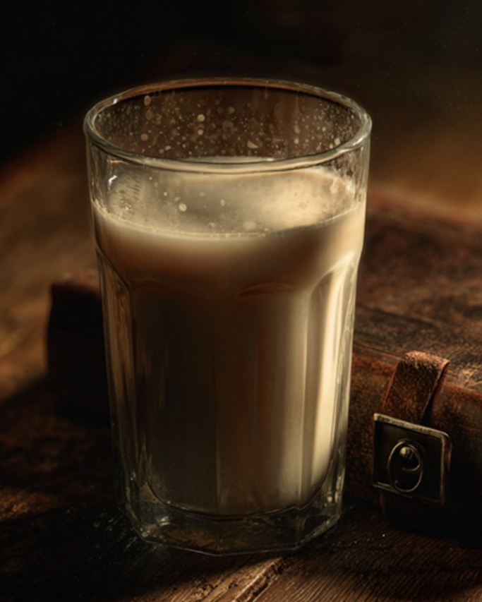 Glass of milk on an old book with a warm, vintage feel